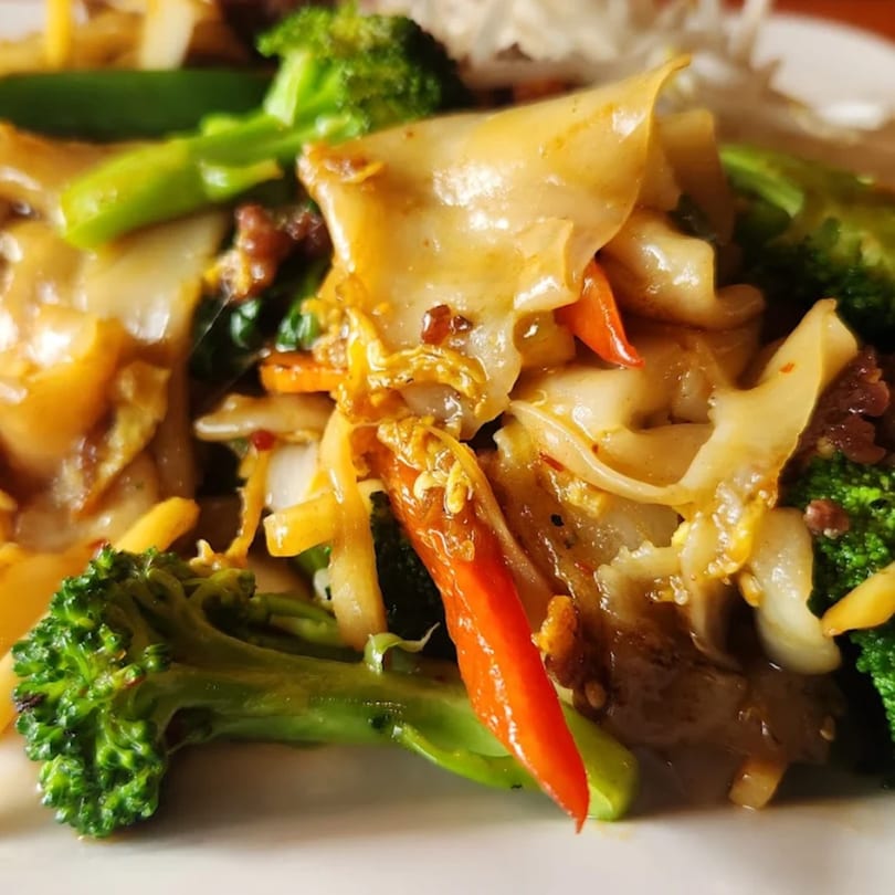 Close-up of Tong Thai's Pad See Ew with wide noodles, broccoli, and red bell peppers.