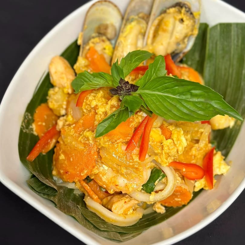 Tong Thai's yellow curry seafood with mussels, squid, shrimp, carrots, and basil on banana leaves.